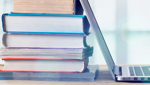 Various books stacked up against an open laptop Various books stacked up against an open laptop